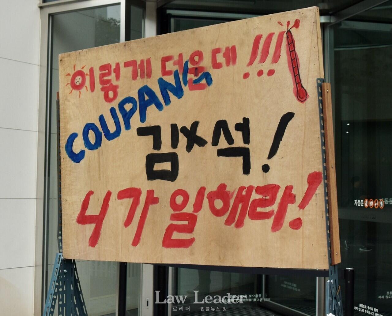 “이렇게 더운데, 쿠팡 김범석 니가 일해라”라고 적힌 판넬이 쿠팡 본사 앞에 있다.
