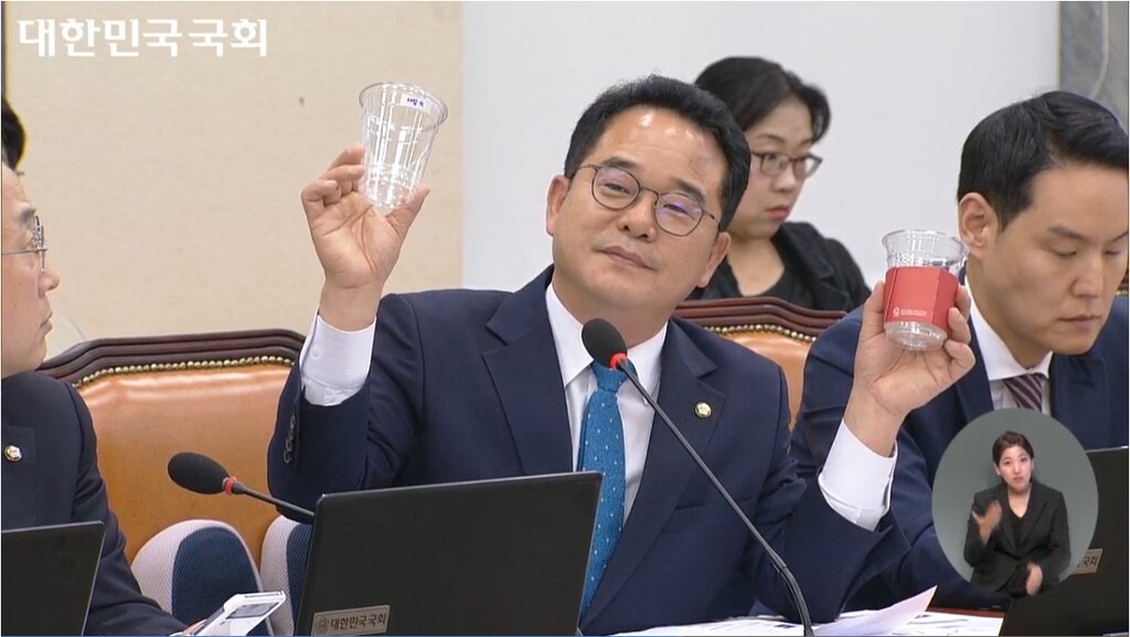 민병덕 국회의원이 시중 판매 중인 컵과 할리스 가맹품목으로 지정된 컵을 들고 질의하고 있다.(국회방송 화면)