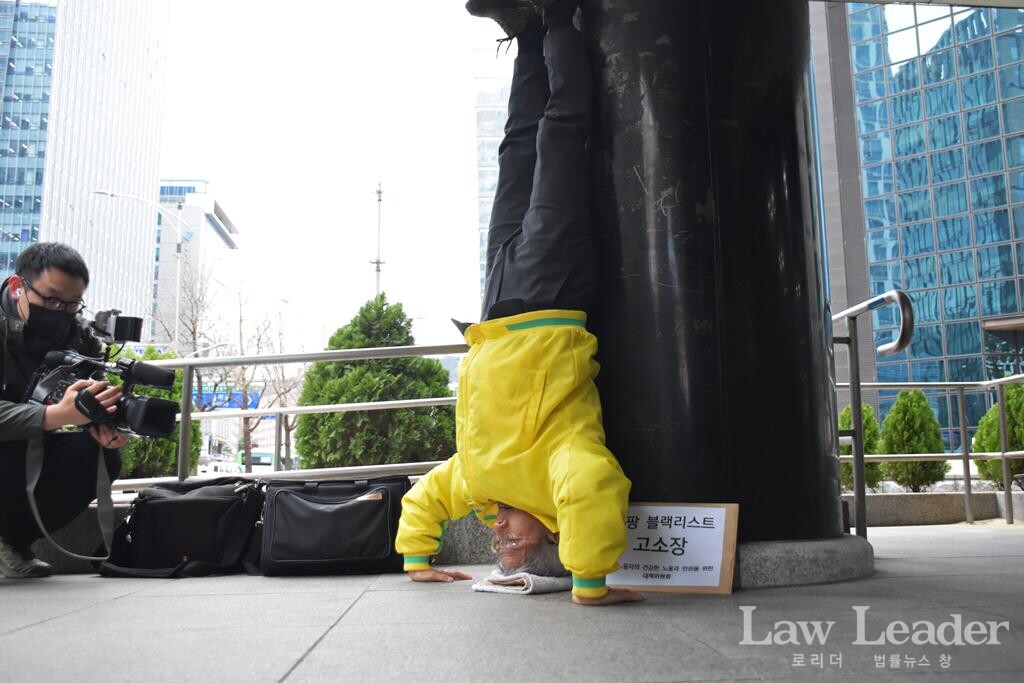 쿠팡대책위 대표인 권영국 변호사가 물구나무 항의시위를 하고 있다.