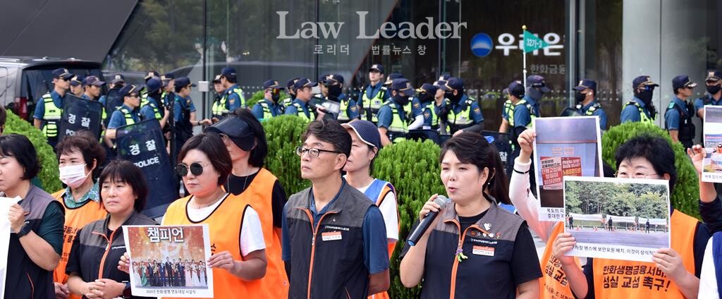 김태은 사무금융노조 보험설계사지부 한화생명지회장이 발언하는 뒤로 경찰들이 방패를 들고 지나가고 있다.