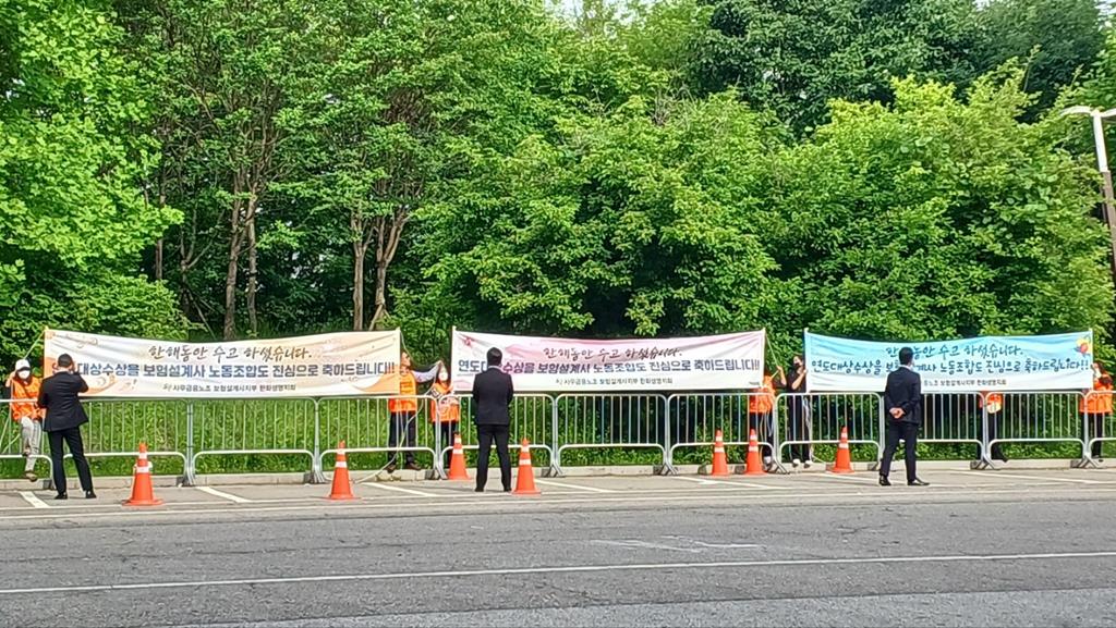 한화생명지회 조합원들이 빈 주차장 밖에서 축하 문구가 적힌 피켓을 들고 있다. (사진=한화생명지회)