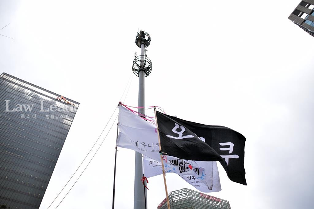 ‘말벌 동지’들이 들고 참석한 ‘아무 깃발’ 뒤로 김형수 지회장의 고공농성장이 있다.