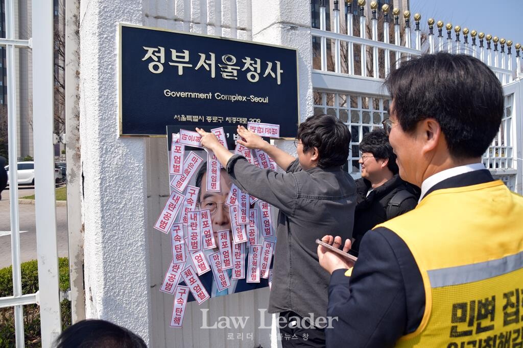 김주호 참여연대 민생경제팀장이 팻말을 붙이는 모습을 김남주 민변 민생경제위원장(변호사)이 바라보고 있다.