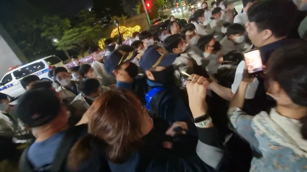 베이지 색 옷을 입은 현대차 구사대와 이수기업 해고노동자 및 연대시민들이 충돌하는 과정에서 모자를 쓴 경찰이 구사대가 아닌 노동자와 시민 측을 바라보고 대응하고 있다(사진=유튜브 채널 “이수기업해고자” 영상 캡처)